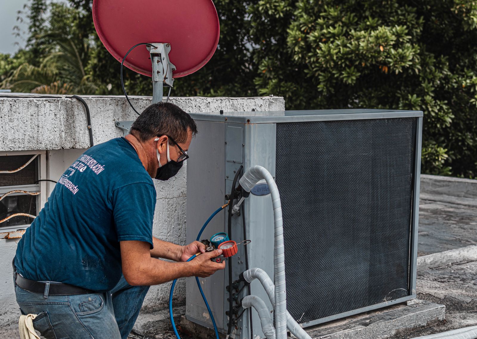 Technician using a manifold gauge to service an outdoor air conditioning unit